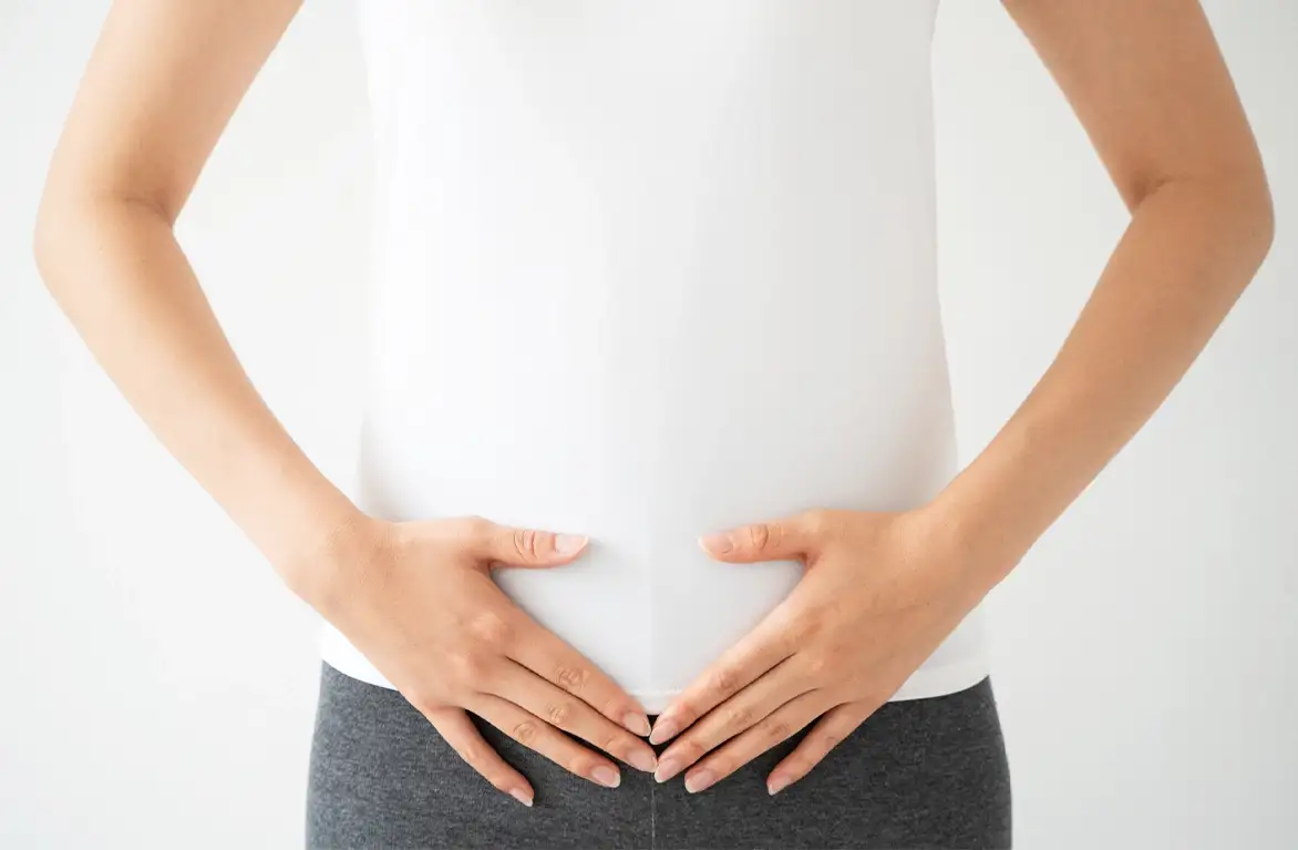 下腹部に両手を当てる女性