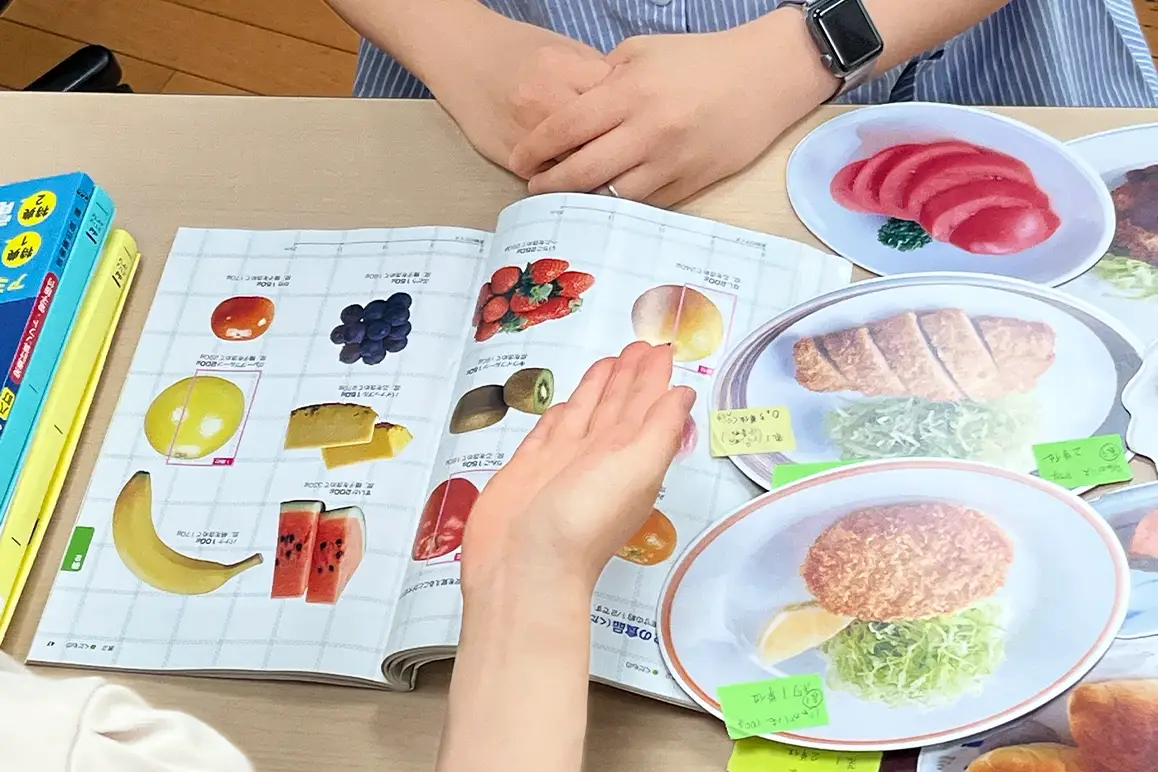 食事の見本と栄養ガイドを使って説明する管理栄養士