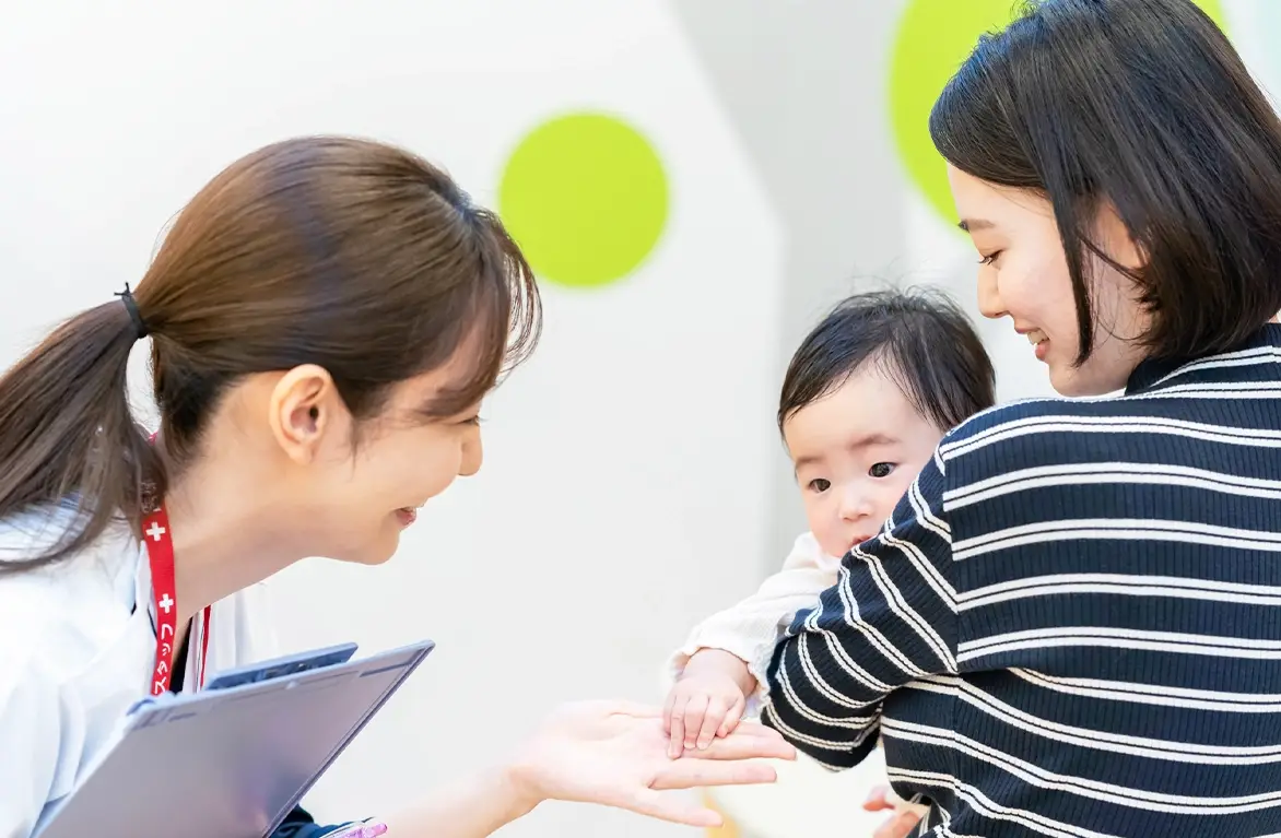 赤ちゃんを抱っこするお母さんと相談するスタッフ